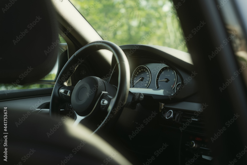 Black premium car interior. Dashboard, steering wheel, speedometer at sunny day
