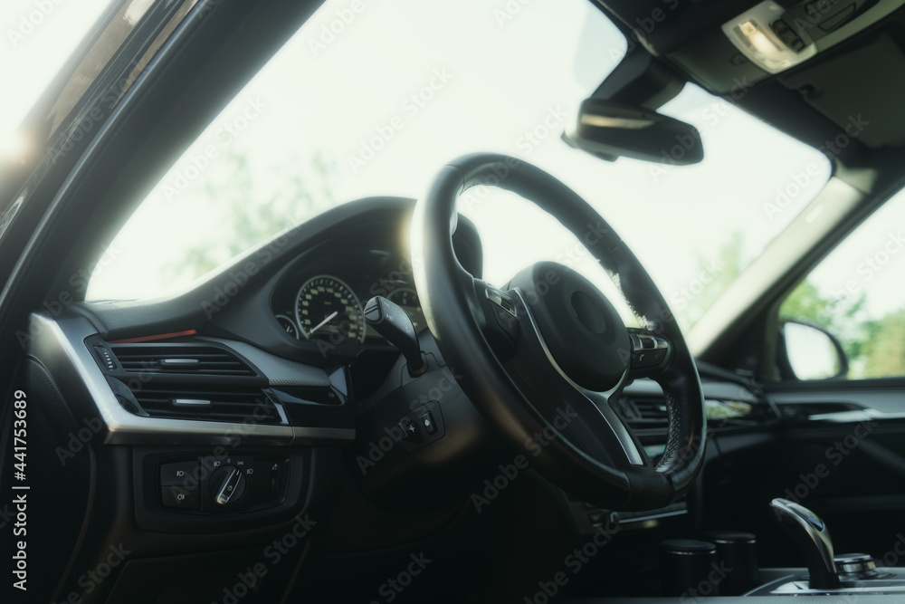 Black premium car interior. Dashboard, steering wheel, speedometer at sunny day Black premium car interior. Dashboard, steering wheel, speedometer at sunny day
