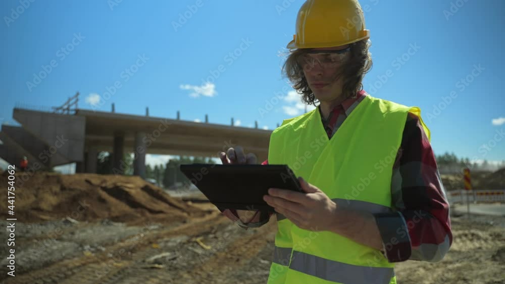 Builder with tablet pc at road junction construction site. Builder with tablet pc at road junction construction site.
