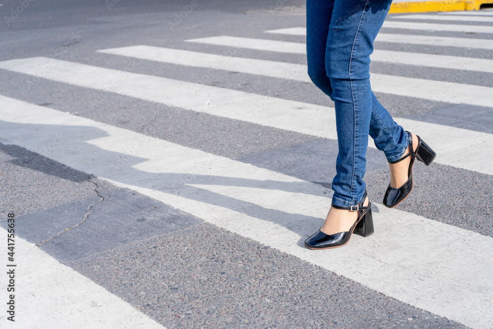 Woman's legs with shoes and pants crossing a street on the pedestrian path or zebra crossing. Woman's legs with shoes and pants crossing a street on the pedestrian path or zebra crossing.