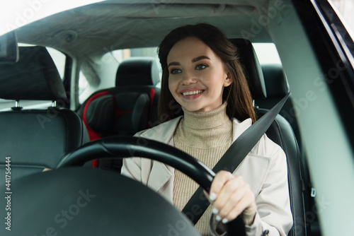 pleased woman driving automobile in city on blurred foreground