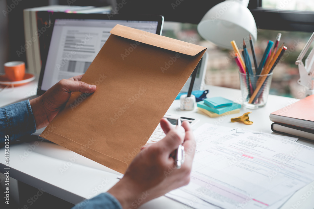 Fototapeta premium Businessman holding document envelope on desk table.