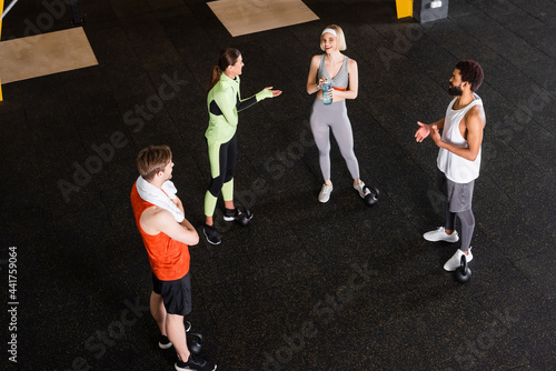 high angle view of smiling interracial people in sportswear talking in gym