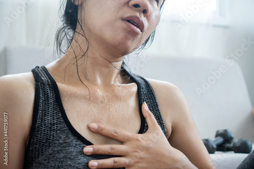 tired Asian woman having heart attack after doing sport hand holding her chest pain that sweat from overtraining photo
