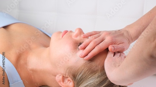 Facial massage beauty treatment. Close up of a young womans face lying on back, getting face lifting massage, pinch and roll technique