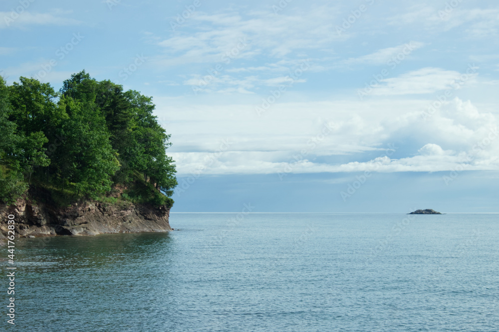 Tree covered island with a smaller island in the background Tree covered island with a smaller island in the background