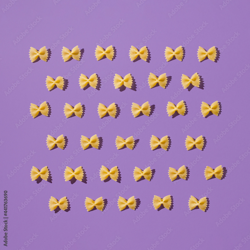 Creative layout of homemade farfalle. Fun and bright food concept. Italian pasta on purple background. Creative layout of homemade farfalle. Fun and bright food concept. Italian pasta on purple background.