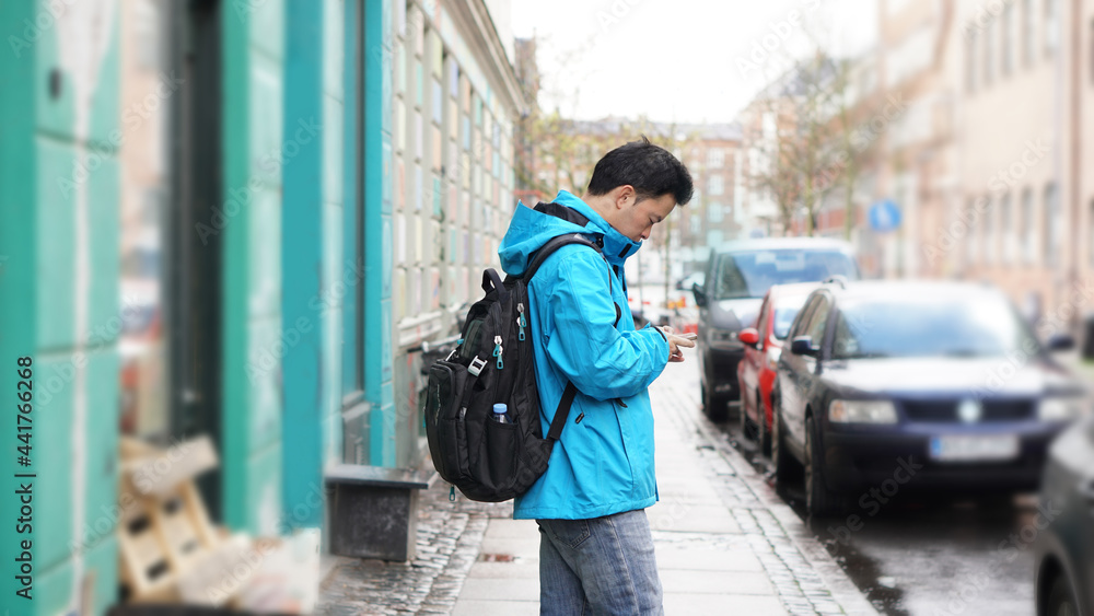 Asian man blue jacket backpack travel to Europe lost searching street on internet mobile Asian man blue jacket backpack travel to Europe lost searching street on internet mobile