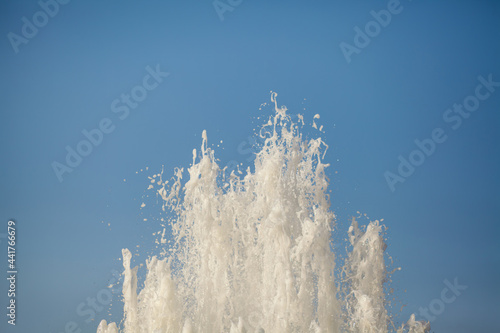 Large jet of water from the fountain on a blue background. Space for text.