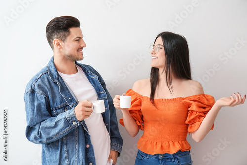Young couple drinking coffee on light background