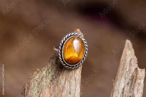 Brass metal tiger eye mineral stone ring on natural background