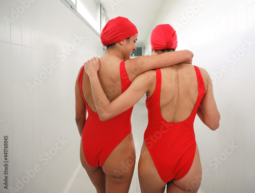 Unrecognizable sportswomen in swimsuits embracing in hallway photo