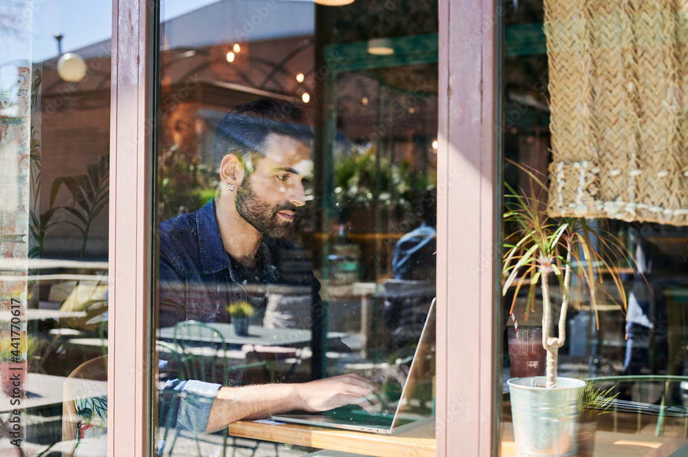 Man ethnic entrepreneur typing on laptop in restaurant Man ethnic entrepreneur typing on laptop in restaurant