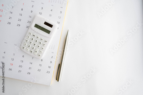 close up top view on calculator with calendar and pen on white background with copy space for business and financial activity monthly concept photo