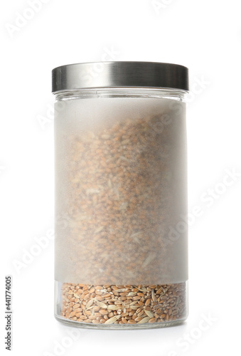 Glass jar with wheat grains on white background