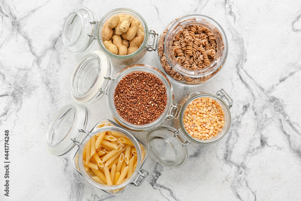 Glass jars with different products on light background Glass jars with different products on light background