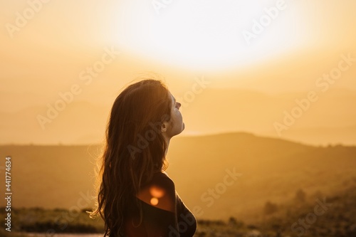 Carefree woman standing on hill and enjoying freedom photo