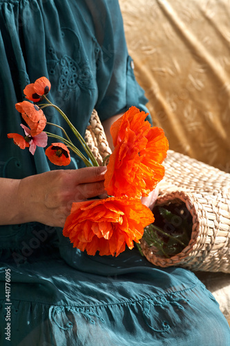 Woman in green dress holding poppe flowers, close up on her hands. Spring time dreams.