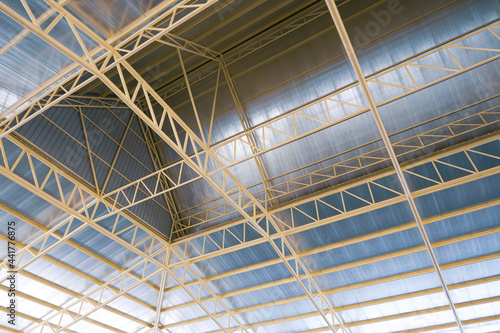 View from below of metal warehouse building roof structure with heat insulations inside of construction site