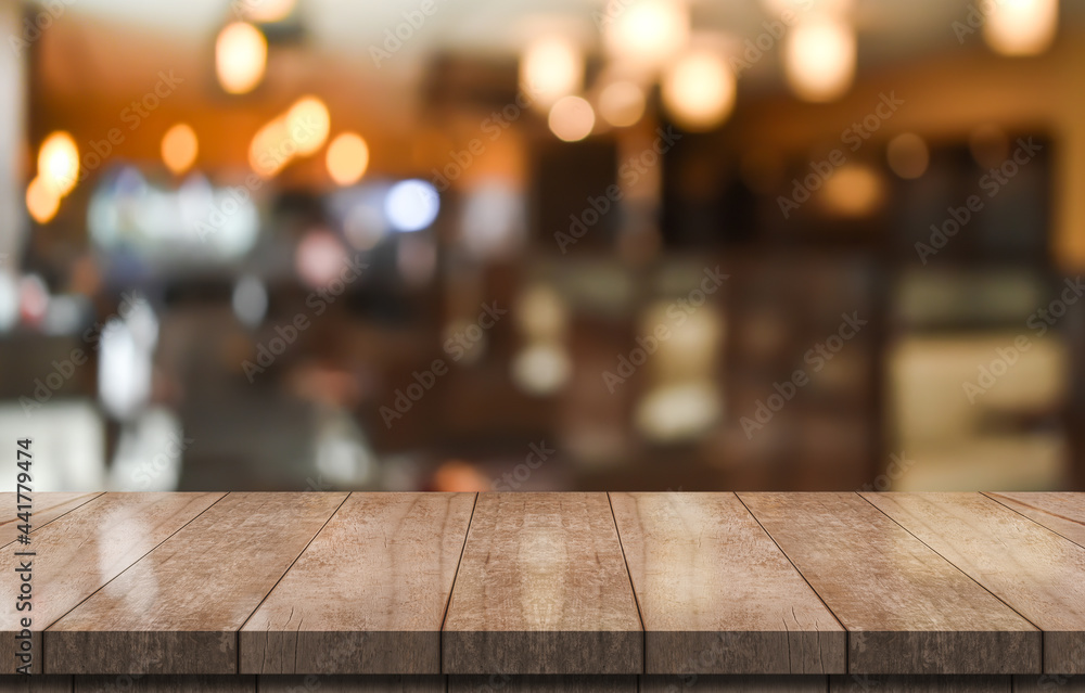 Empty wooden table top with lights bokeh on blur restaurant background.