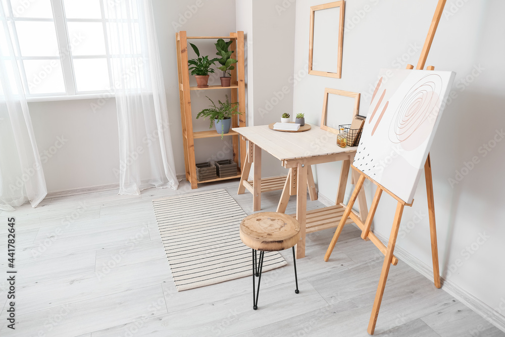 Fototapeta premium Modern workplace and easel in interior of stylish room