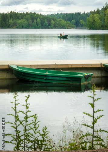 Green boat waiting for customer in the background young couple paddling canoe in swedish lake near gothenburg