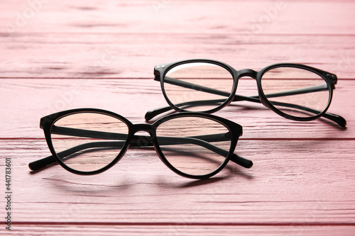 Different stylish eyeglasses on color wooden background, closeup