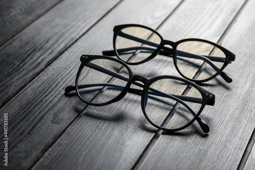 Different stylish eyeglasses on grey wooden background, closeup