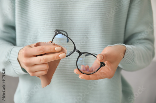 Woman wiping stylish eyeglasses, closeup