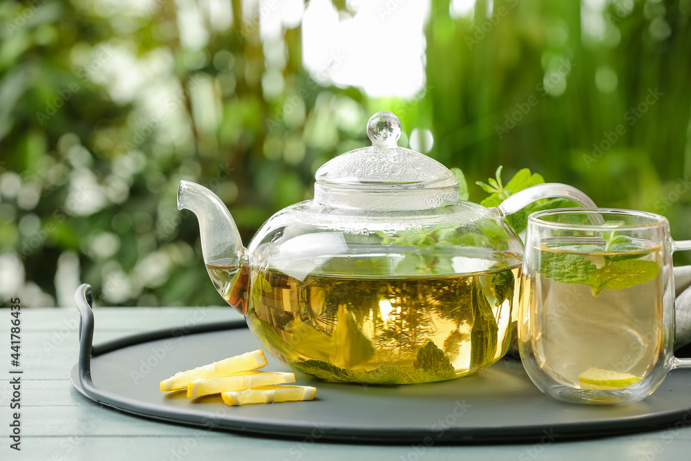 Tray with cup of tasty green tea and pot on table outdoors Tray with cup of tasty green tea and pot on table outdoors