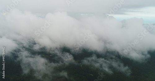 AERIAL. Flight above tropical island throught clouds and top view of mountains and forest. Thailand.