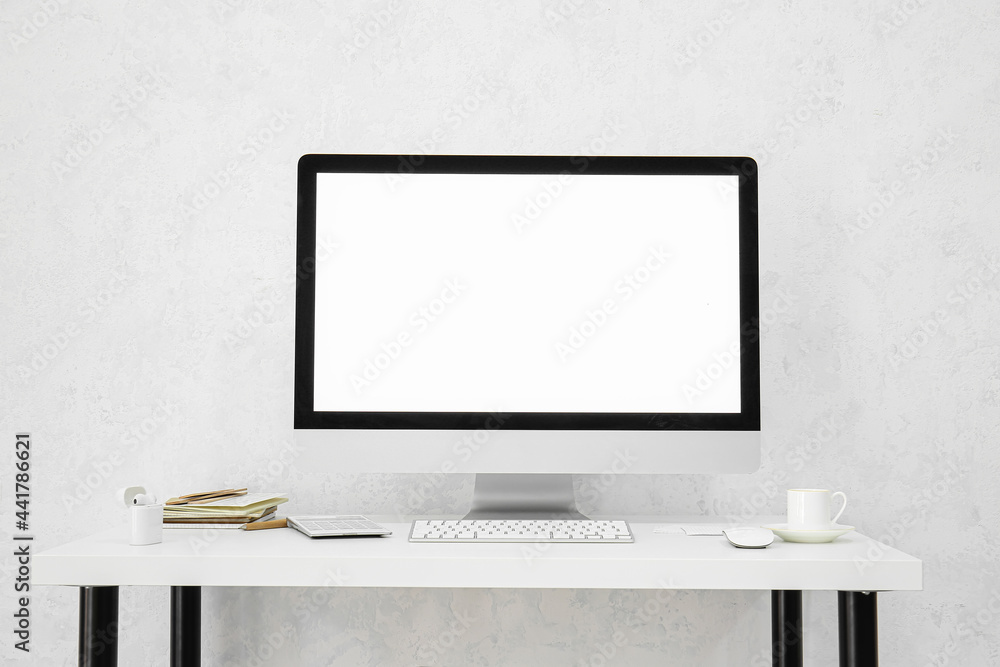 Fototapeta premium Stylish workplace with modern computer on table near light wall