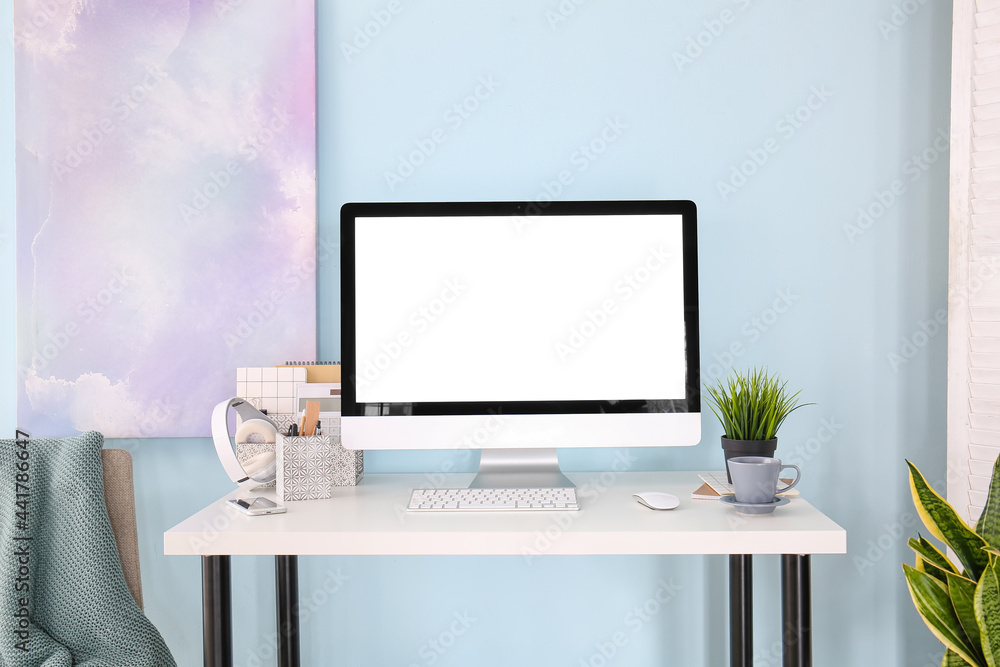 Stylish workplace with modern computer on table near color wall Stylish workplace with modern computer on table near color wall