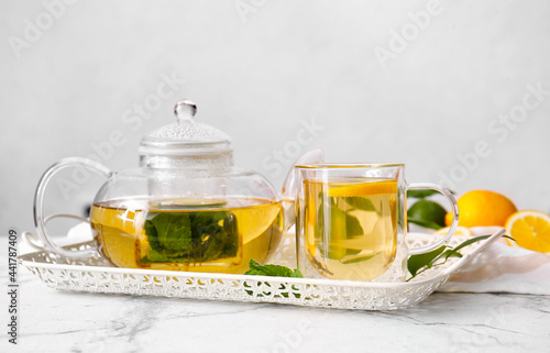 Tray with cup of tasty green tea and pot on light table