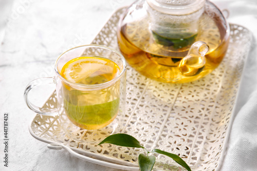 Tray with cup of tasty green tea and pot on light table