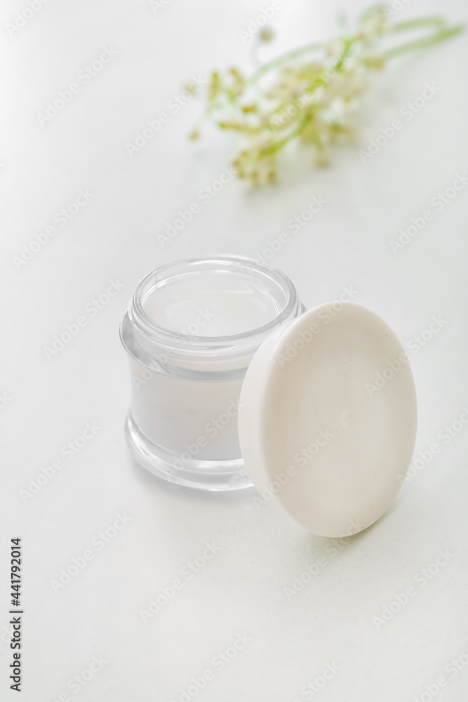Jar of cream and lily-of-the-valley flowers on light background Jar of cream and lily-of-the-valley flowers on light background