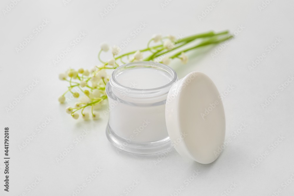 Jar of cream and lily-of-the-valley flowers on light background Jar of cream and lily-of-the-valley flowers on light background