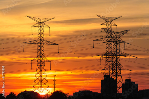 Electric poles and power lines in a Canadian suburban area on an orange vibrant sunset sky background
