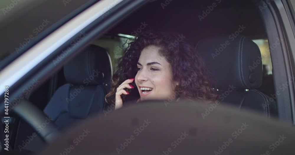 Smiling caucasian woman talking on phone, touching steering wheel and looking around inside automobile. Successful young woman buy vehicle in car dealership. Portrait of a woman in a car with a phone. Smiling caucasian woman talking on phone, touching steering wheel and looking around inside automobile. Successful young woman buy vehicle in car dealership. Portrait of a woman in a car with a phone.