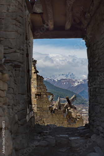 Russia. North-Eastern Caucasus, Dagestan. View of the Caucasus Mountains through the doorway of an abandoned house in the mountain village of Khushtada. Traditionally, all houses are made of stone.