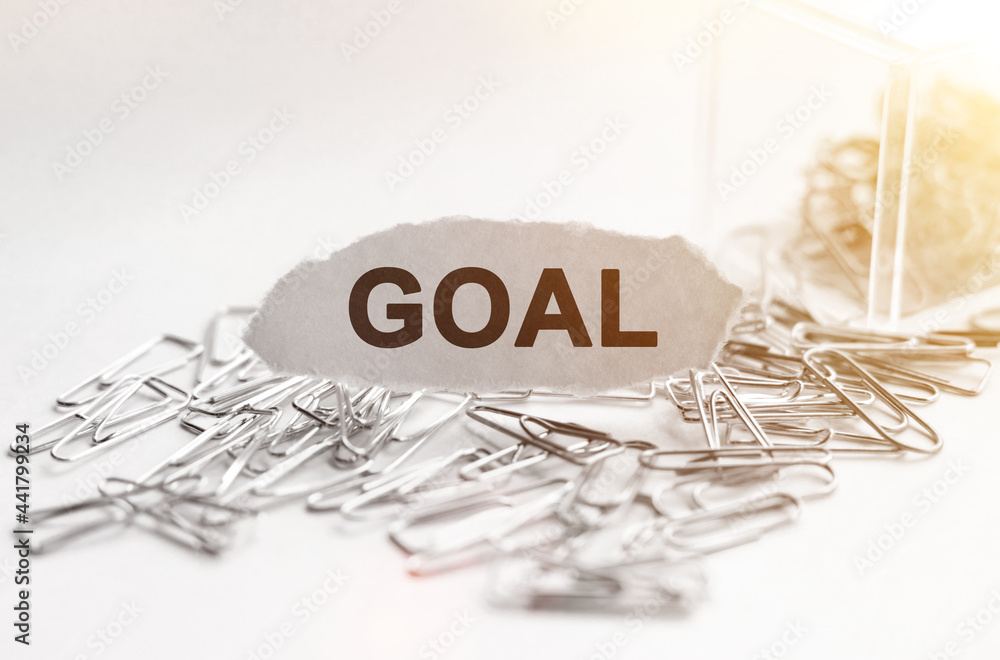 Fototapeta premium Paper clips are scattered on the table and there is paper with the inscription - GOAL