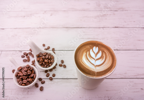 Hot cappuccino with roasted coffee beans on a wooden