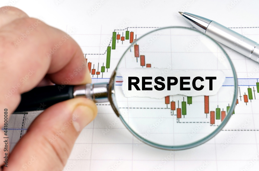 A man looks through a magnifying glass at charts and paper with the inscription - RESPECT A man looks through a magnifying glass at charts and paper with the inscription - RESPECT
