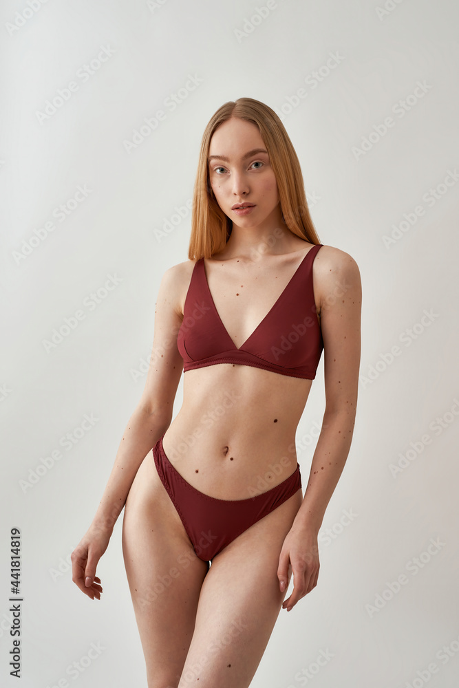 Attractive young slim caucasian woman with beautiful perfect body wearing burgundy underwear posing isolated over light gray background Attractive young slim caucasian woman with beautiful perfect body wearing burgundy underwear posing isolated over light gray background