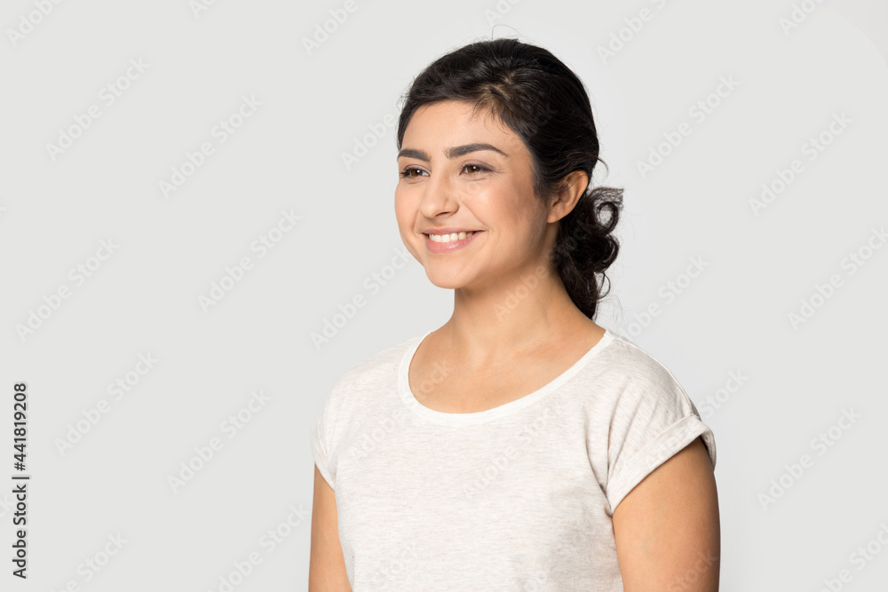 Side view of smiling Indian young woman isolated on grey studio background look in distance dreaming thinking. Happy mixed race female make plan or visualize imagine. Planner, vision concept. Side view of smiling Indian young woman isolated on grey studio background look in distance dreaming thinking. Happy mixed race female make plan or visualize imagine. Planner, vision concept.