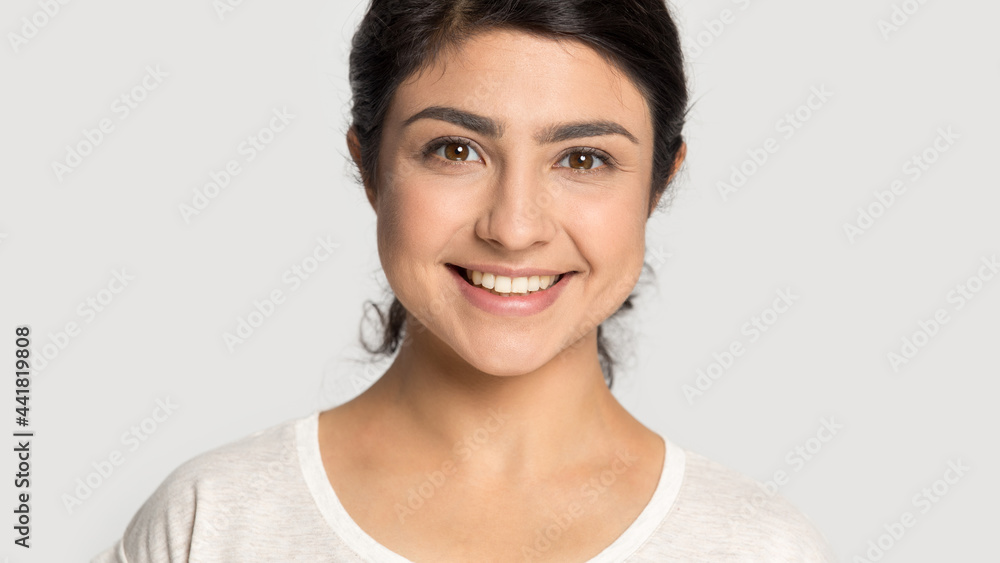 Close up portrait of happy millennial Indian woman isolated on grey studio background show white healthy event teeth. Smiling mixed race female feel overjoyed with dental treatment. Diversity concept. Close up portrait of happy millennial Indian woman isolated on grey studio background show white healthy event teeth. Smiling mixed race female feel overjoyed with dental treatment. Diversity concept.
