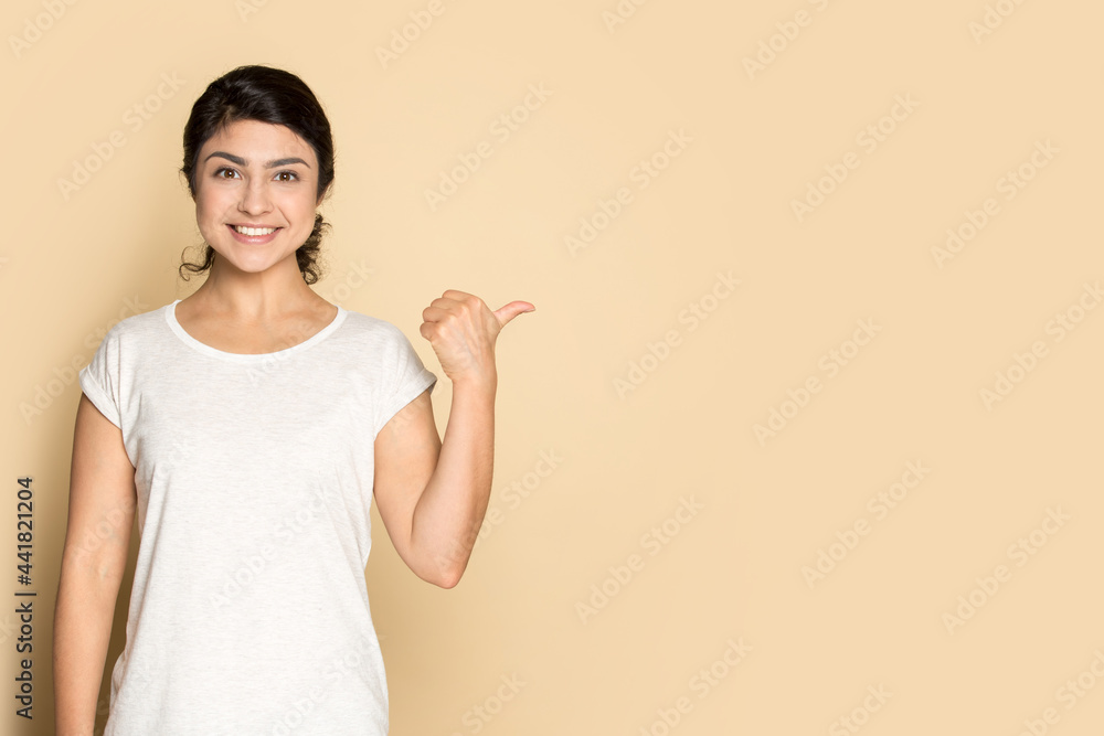 Portrait of smiling young Indian young woman isolated on yellow studio background show pint at empty vacant copy space. Happy mixed race female recommend good deal or promotion discount offer. Portrait of smiling young Indian young woman isolated on yellow studio background show pint at empty vacant copy space. Happy mixed race female recommend good deal or promotion discount offer.