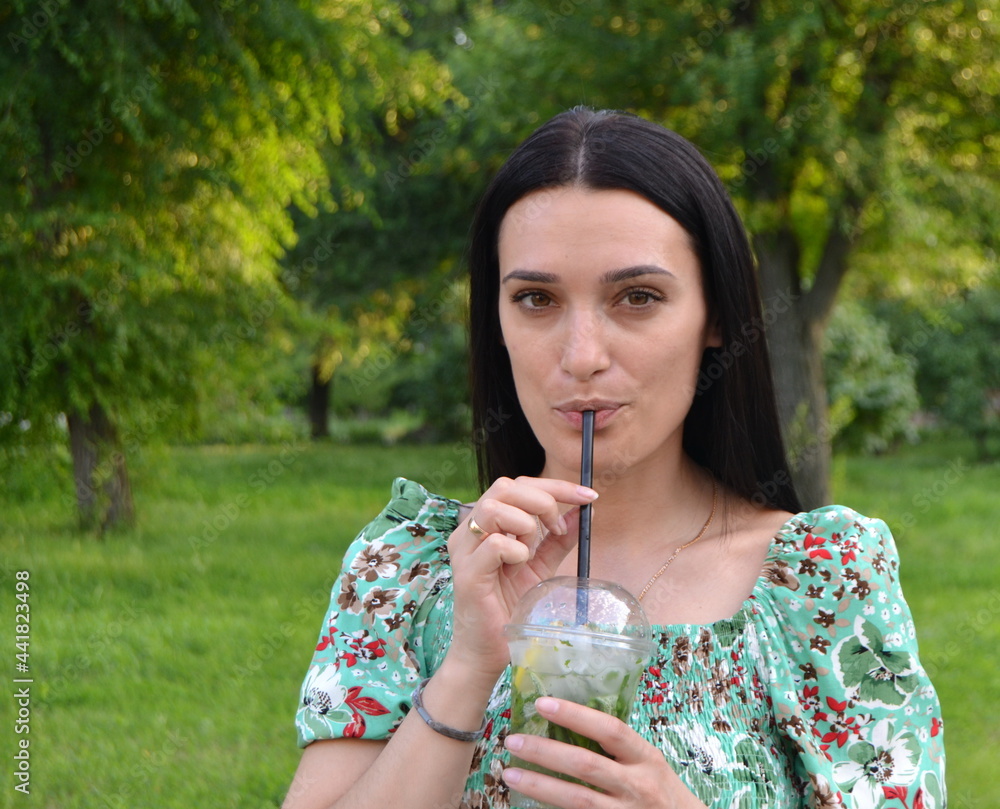 Woman drinks mojito in the park in summer. Woman drinks mojito in the park in summer.