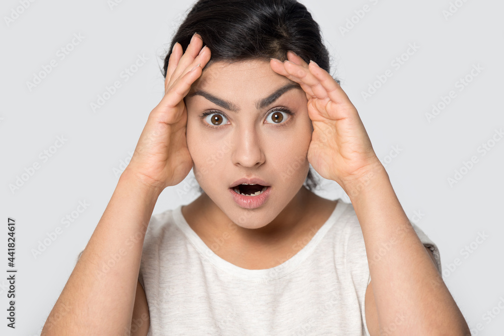 Close up portrait of shocked young Indian woman isolated on grey studio background hear unexpected unbelievable news. Stunned mixed race female surprised by sale offer or promotion deal. Close up portrait of shocked young Indian woman isolated on grey studio background hear unexpected unbelievable news. Stunned mixed race female surprised by sale offer or promotion deal.