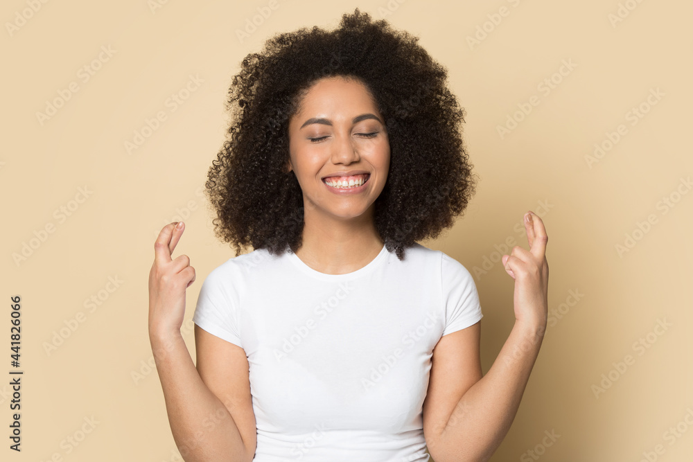 Smiling young African American woman isolated on yellow studio background cross fingers make wish. Happy millennial mixed race female feel excited optimistic for dream come true. Luck concept. Smiling young African American woman isolated on yellow studio background cross fingers make wish. Happy millennial mixed race female feel excited optimistic for dream come true. Luck concept.